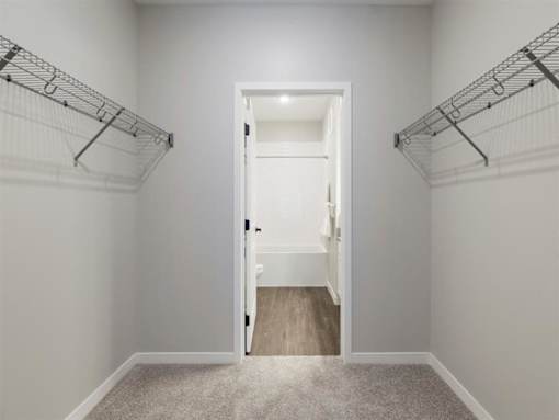 A white door is open to a hallway with a carpeted floor at The Barnum Apartments, White Bear Lake, MN,  55110
