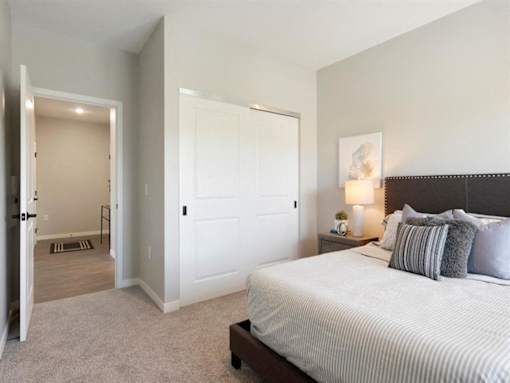 A bedroom with a large bed and a nightstand with a lamp at The Barnum Apartments, Minnesota, 55110