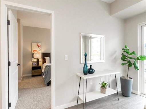 A bedroom with a bed, nightstand, and a mirror on the wall at The Barnum Apartments, MN, 55110