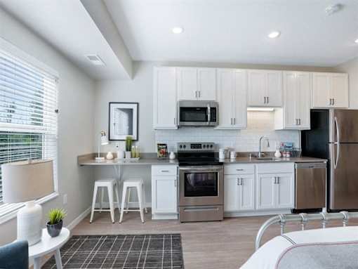 A kitchen with white cabinets and stainless steel appliances at The Barnum Apartments, White Bear Lake