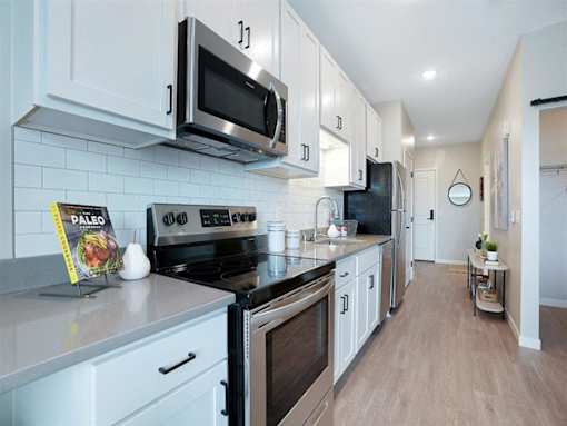 A kitchen with white cabinets and a black stove top oven at The Barnum Apartments, Minnesota