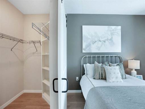 A bedroom with a bed, pillows, a lamp, and a painting on the wall at The Barnum Apartments, Minnesota, 55110