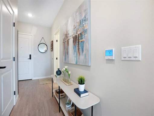 A hallway with a white table and a painting on the wall at The Barnum Apartments, White Bear Lake