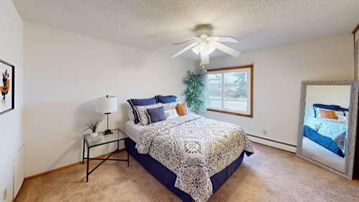 A bedroom with a bed, a ceiling fan, and a window.