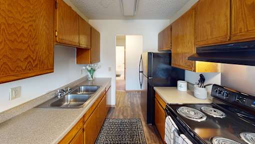 A kitchen with wooden cabinets and a black refrigerator.