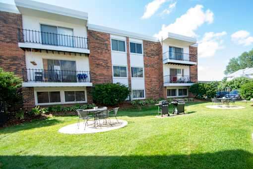 A building with a balcony and a table and chairs in the front yard.