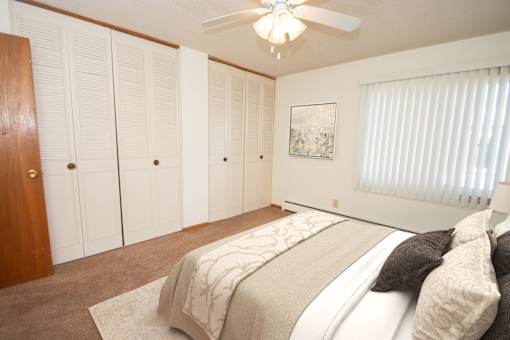 A bedroom with a large bed and a ceiling fan.