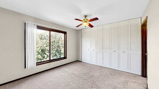 A room with a ceiling fan and a window with curtains.