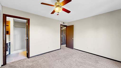 A room with a ceiling fan and carpeted floor.
