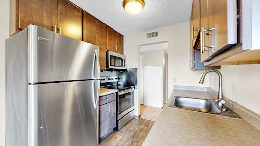 A kitchen with a stainless steel refrigerator and a microwave above the stove.