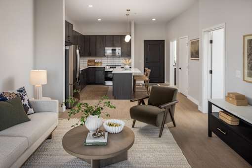 A modern living room with a grey sofa, a coffee table, and a kitchen in the background.