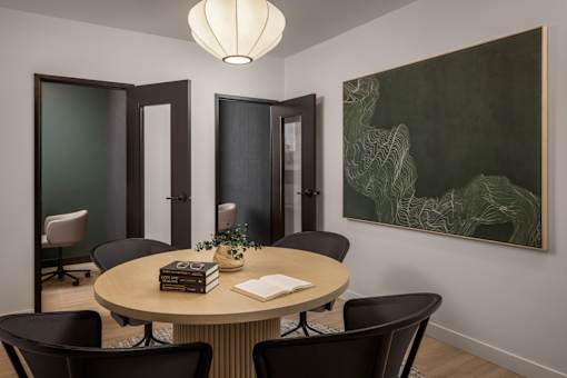 A conference room with a round table surrounded by chairs.
