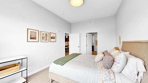 A bedroom with a bed, pillows, and pictures on the wall.