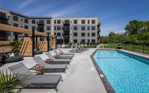 A swimming pool surrounded by lounge chairs and a building in the background.