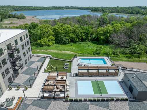 A large outdoor swimming pool with a green grassy area and a building in the background.