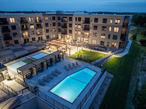 A large apartment complex with a pool and lounge area.