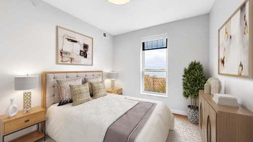 A bedroom with a large bed, a nightstand, and a window.