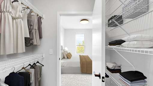 A white closet with clothes hanging and a doorway leading to a bedroom.