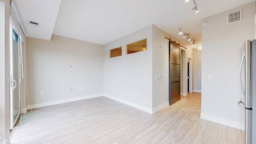 A spacious room with white walls and wooden flooring.