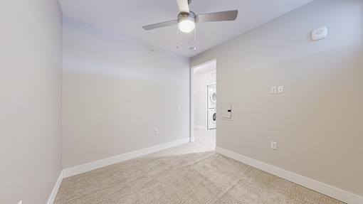 A room with a ceiling fan and carpeted floor.
