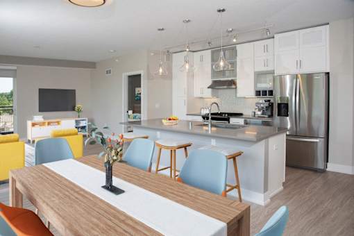 A modern kitchen with a wooden table and blue chairs.