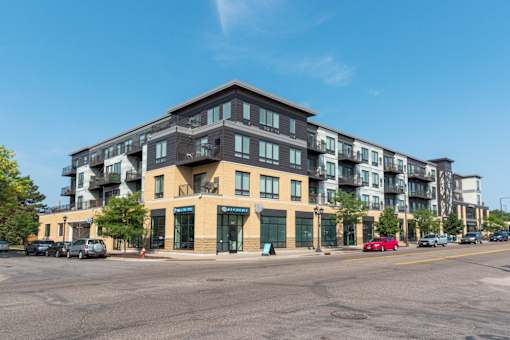 A large apartment building with a parking lot in front.