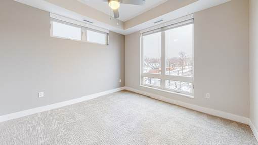 A room with a carpeted floor and a ceiling fan.