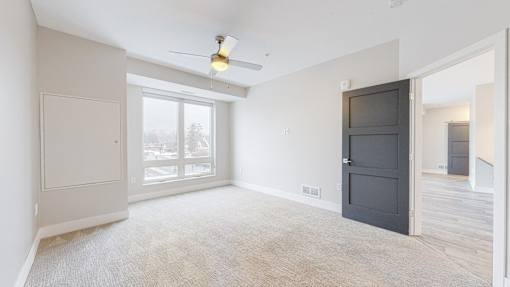 A room with a ceiling fan and a large window.
