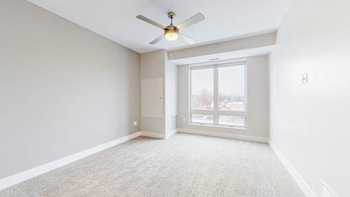 A room with a ceiling fan and a sliding glass door.