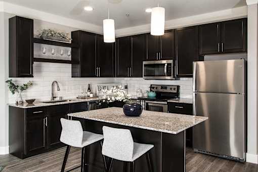 A modern kitchen with a granite countertop and stainless steel appliances.