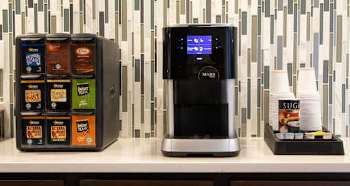 A vending machine with a variety of snacks and a coffee machine on a counter.