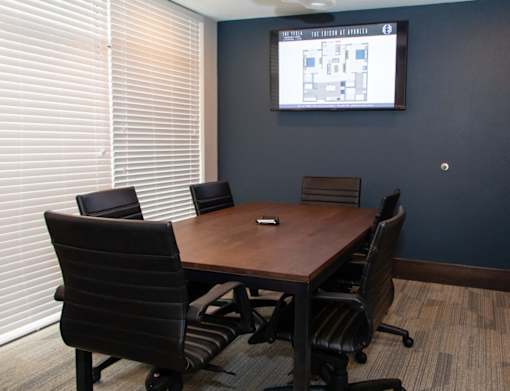 A conference room with a large screen and chairs.