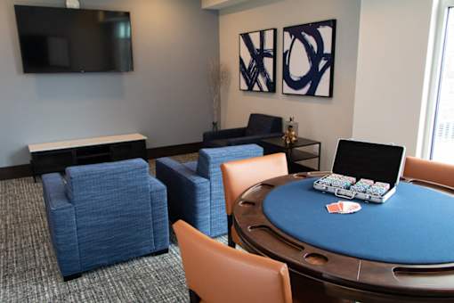 A poker table with chairs and a television in the background.