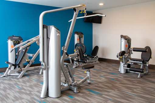 A gym with a blue wall and a variety of exercise equipment.