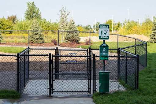 A sign on a post in front of a fence indicates a pet waste area.