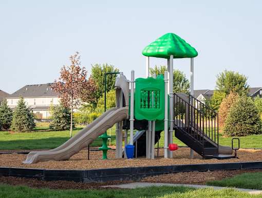 A playground with a green slide and a green umbrella.