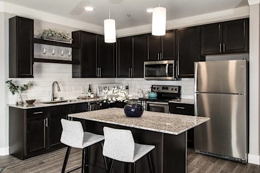 A modern kitchen with a granite countertop and stainless steel appliances.