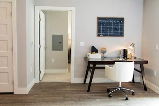 A white chair is in front of a desk with a black frame.