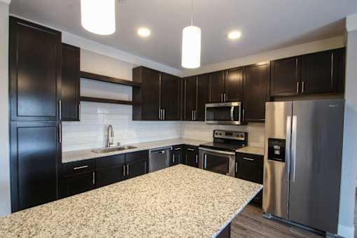 A kitchen with black cabinets and a granite countertop.