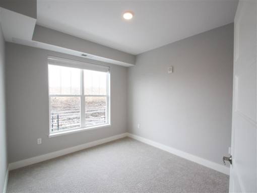 A room with a carpeted floor and a window.