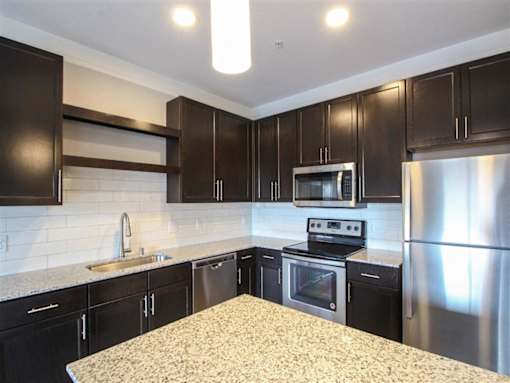 A kitchen with black cabinets and stainless steel appliances.