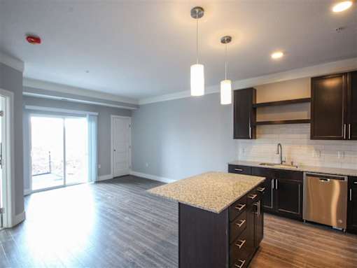 A kitchen with a granite countertop and wooden cabinets.
