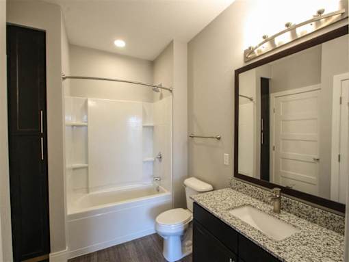 A white toilet sits in a bathroom next to a sink and a bathtub.