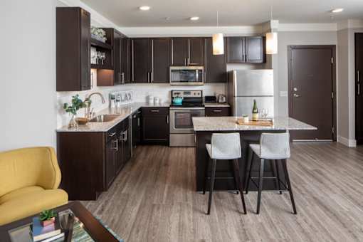 A modern kitchen with dark brown cabinets and a yellow chair.