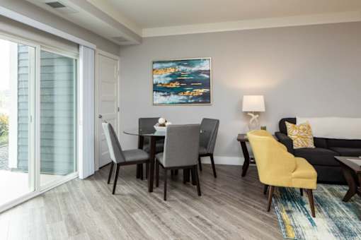 A modern living room with a grey sofa, a grey dining table and a yellow chair.