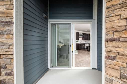 A glass door leads to a room with a dining table and chairs.