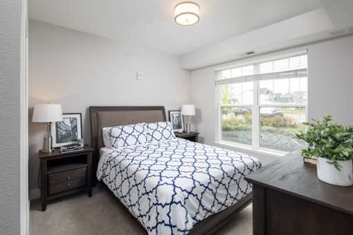 A bedroom with a bed, nightstand, and window.
