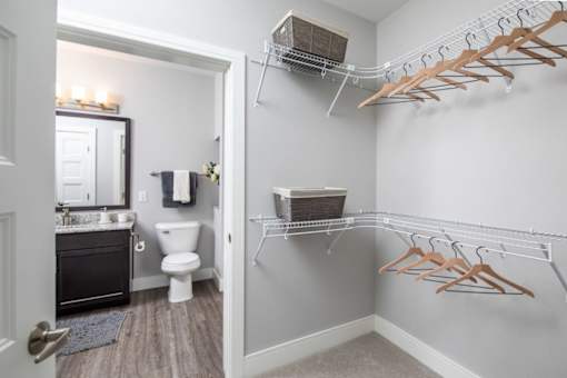 A bathroom with a toilet, sink, and clothes hangers.