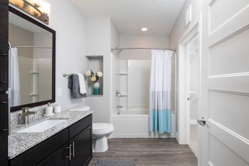 A bathroom with a white toilet, a sink, a bathtub, and a white door.
