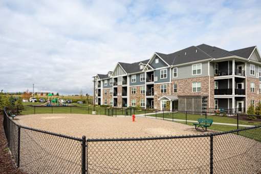 A large building with a fenced in playground in front.
